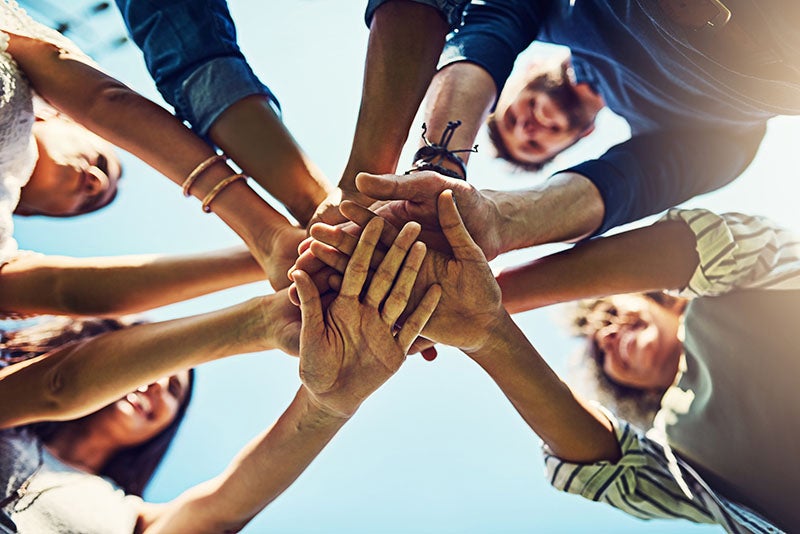 group of people stacking hands togther